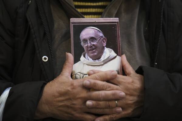 A faithful holds a portrait of late Pope Francis at the Basílica de San José de Flores, where he worshipped as a youth, following the Vatican's announcement of his death in Buenos Aires, Argentina, Monday, April 21, 2025. (AP Photo/Gustavo Garello)