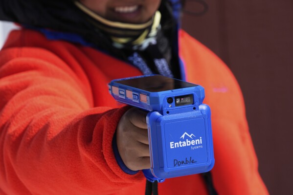 Lift attendant Veronica Crespo Jimenez uses a handheld device to scan a skier's pass, which is embedded with an RFID chip, at Black Mountain, Friday, March 14, 2025, in Jackson, N.H. (AP Photo/Charles Krupa)