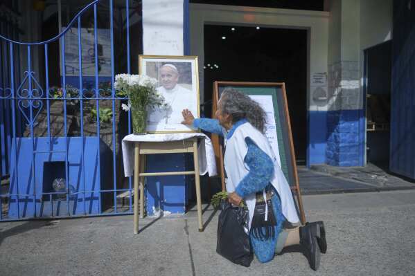 Gregoria Caceres kneels in front of a portrait of the late Pope Francis at the Caacupe Parish, which he often visited and preached at, in Buenos Aires, Argentina, Monday, April 21, 2025. (AP Photo/Natacha Pisarenko)
