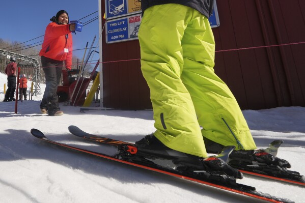 Lift attendant Veronica Crespo Jimenez scans a skier's pass, which are embedded with an RFID chip, at Black Mountain, Friday, March 14, 2025, in Jackson, N.H. (AP Photo/Charles Krupa)