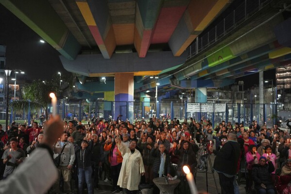 Faithful hold candles under a highway bridge during Mass to honor the late Pope Francis in the Carlos Mugica neighborhood of Buenos Aires, Argentina, Monday, April 21, 2025. (AP Photo/Rodrigo Abd)