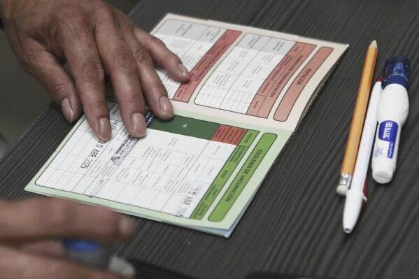 A health worker stamps a vaccination card at the health center where measles vaccinations are given in Ciudad Juarez, Chihuahua state, Mexico, Wednesday, April 30, 2025. (AP Photo/Christian Chavez)