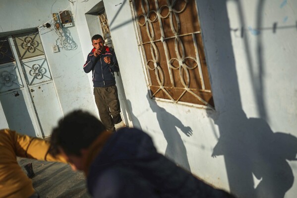 Shepherd Jalal Ma'rouf, 22, who lost a limb to a landmine while herding sheep in farmland recently recaptured from regime forces, watches his friends play at his home in Deir Sunbul village, south of Idlib, Wednesday, April 9, 2025. (AP Photo/Ghaith Alsayed)