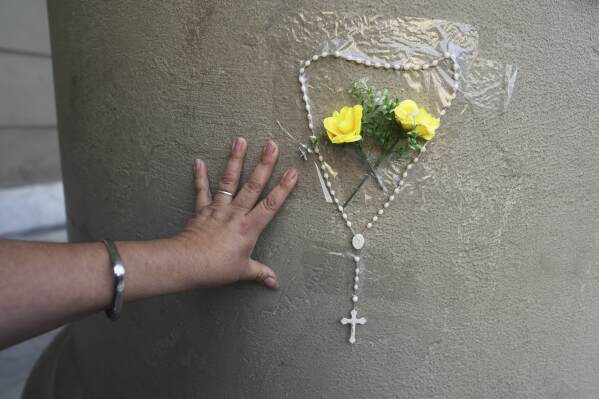 Patricia Sanchez attaches a rosary to a column of the Cathedral following the Vatican's announcement of Pope Francis' death in Buenos Aires, Argentina, Monday, April 21, 2025. (AP Photo/Natacha Pisarenko)