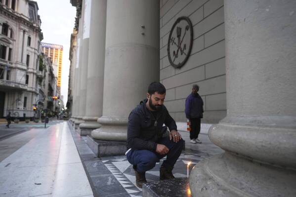 Agustín Hartich lights a candle at the Cathedral following the Vatican's announcement of Pope Francis' death in Buenos Aires, Argentina, Monday, April 21, 2025. (AP Photo/Natacha Pisarenko)