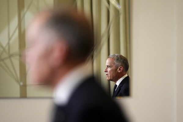 Canada's Prime Minister Mark Carney, reflected in a mirror, speaks to media during a press conference at Canada House in London on March 17, 2025. (Sean Kilpatrick/The Canadian Press via AP, File)